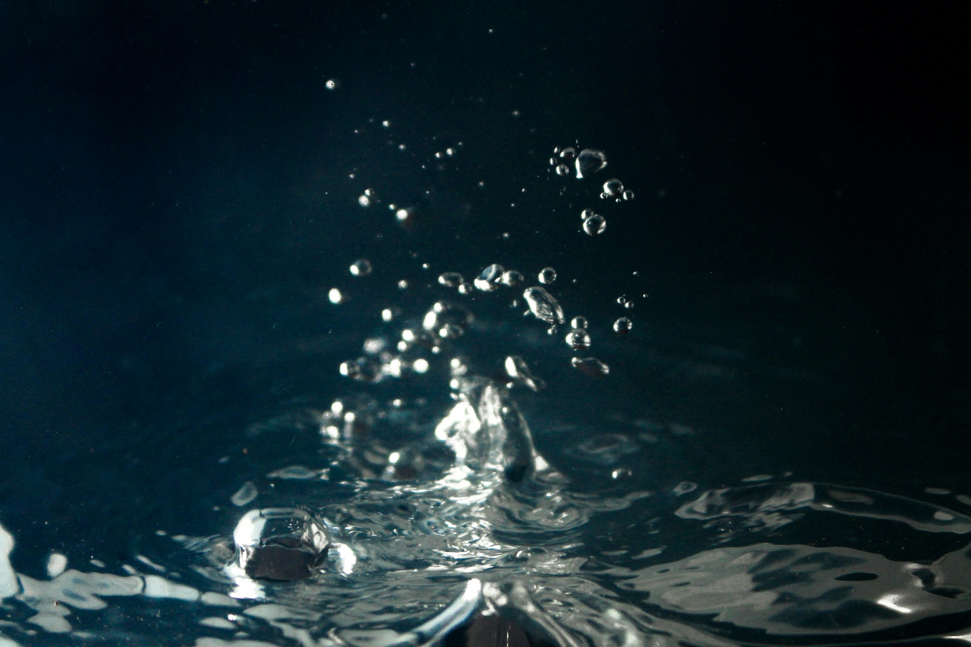 Water droplets suspended over a dark reflective surface